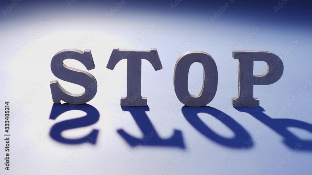 The word stop on a blue surface illuminated by light, the shadow of the word slowly moves on the surface The word stop on a blue surface illuminated by light, the shadow of the word slowly moves on the surface