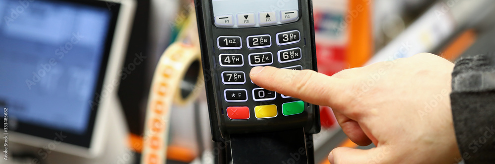 Male hand typing pin code card while paying with it at cash desk of supermarket