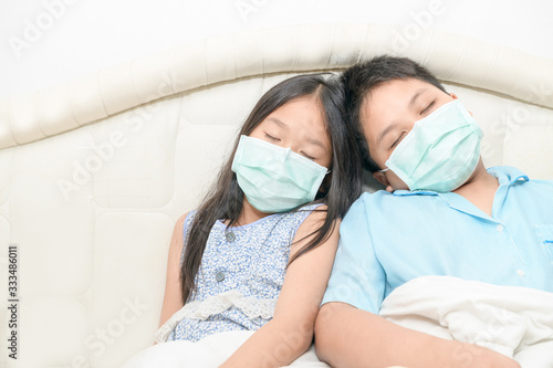 Brother and sister wear surgical mask sleep on bed, Sick child