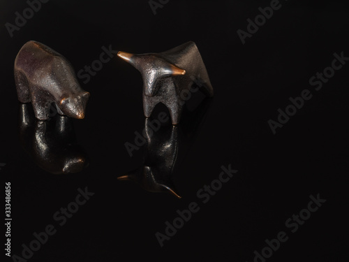 A close up of the stock market symbols, bear and bull on a black background.