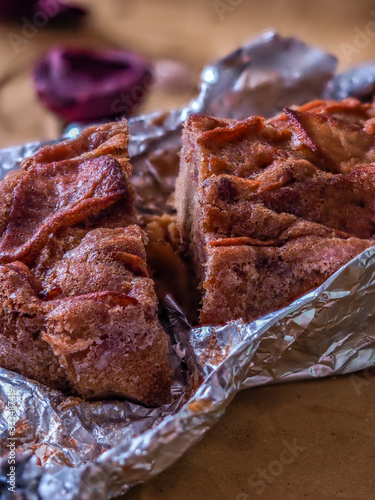 A photo of an whole flour apple pie in allu foil, on a dark rustic brown background with apples and  biologic eggs photo photo