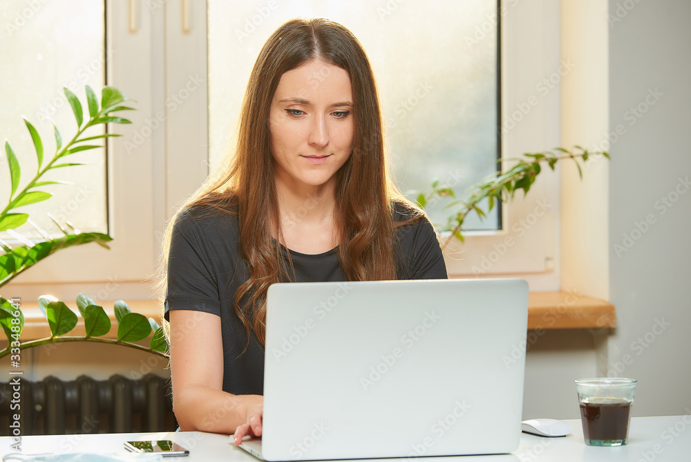 A caucasian woman studying remotely on her laptop during the quarantine to avoid the spread coronavirus. A businesswoman working from home during the pandemic of COVID-19. A caucasian woman studying remotely on her laptop during the quarantine to avoid the spread coronavirus. A businesswoman working from home during the pandemic of COVID-19.