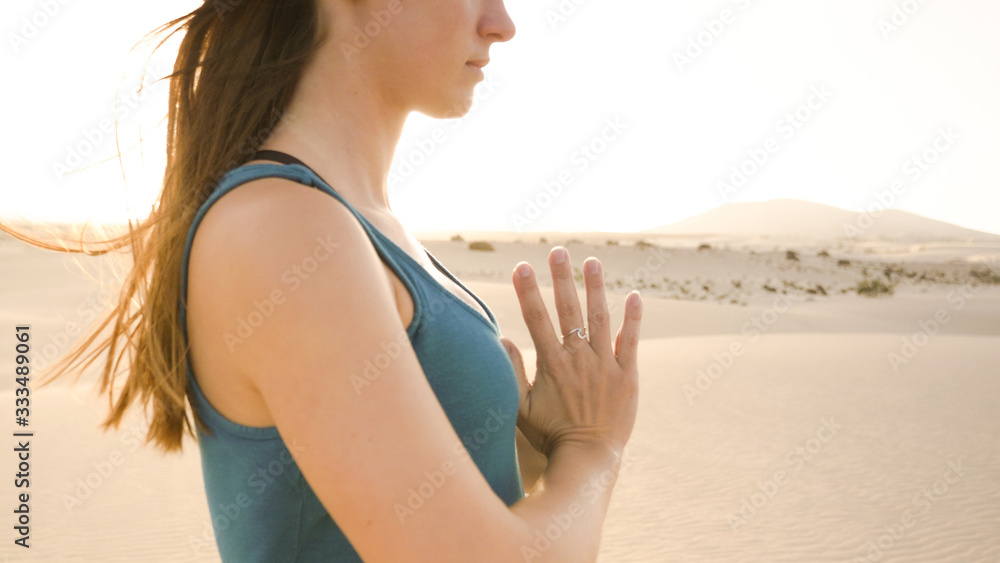 Closeup of young woman meditating in desert. Hands of woman with silver wave ring while practicing yoga.