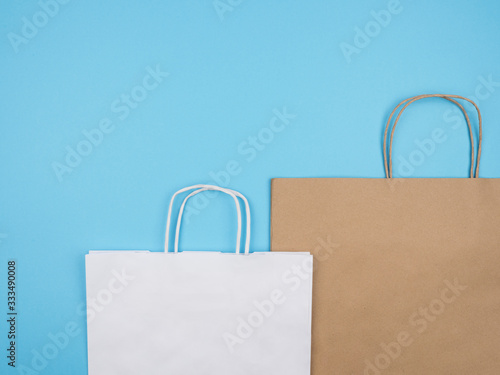 White and brown paper shopping bags on blue background.