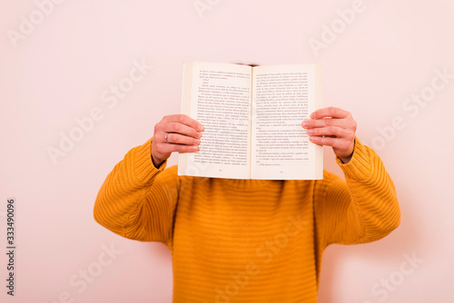Obraz na płótnie chica sosteniendo un libro con una mano delante de la cara