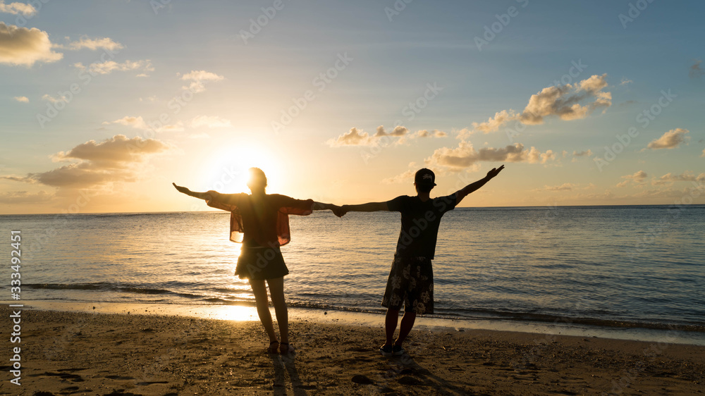 Fototapeta premium Couple kissing on the beach with a beautiful sunset in background, man lifting the woman