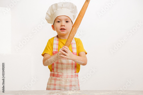 Details of children's hands kneading dough. Cheerful cook child boy in a cap prepares burritos photo