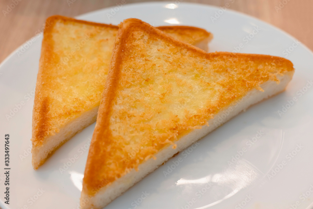 Toasted bread on the white plate and butter on wood table, Popular breakfasts around the world, Tasty and convenient, Selective focus. Toasted bread on the white plate and butter on wood table, Popular breakfasts around the world, Tasty and convenient, Selective focus.