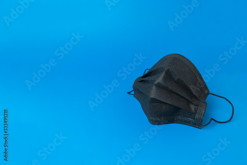 Black medical mask on blue background. Medical mask for protection against flu and other diseases and prevention of the spread of virus and epidemic.