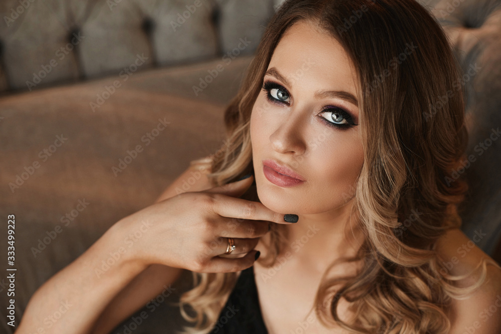 Young woman with blond hair and perfect trendy makeup. Beautiful blonde model girl with modish makeup, deep seductive eyes. Concept of modish official makeup and smooth skin