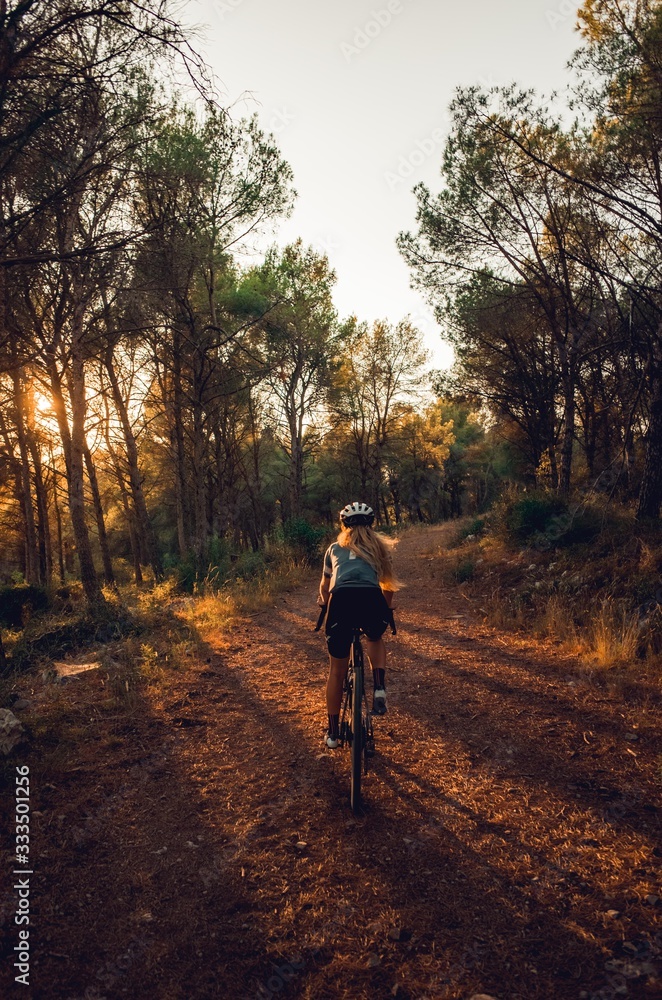 Blonde cyclist riding in forest at sunset