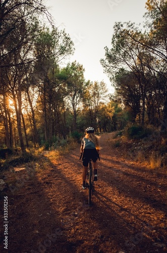Blonde cyclist riding in forest at sunset