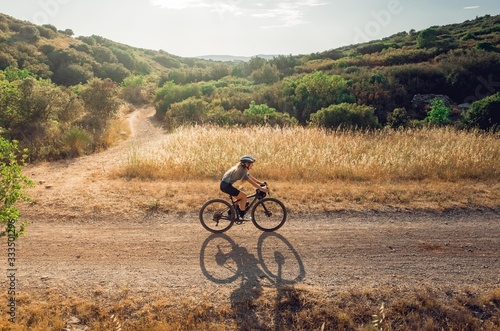 Cyclist riding gravel from side in golden fields photo