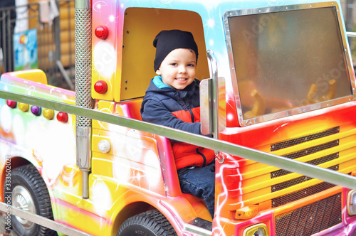 Little boy having fun and riding a train in an amusement park.