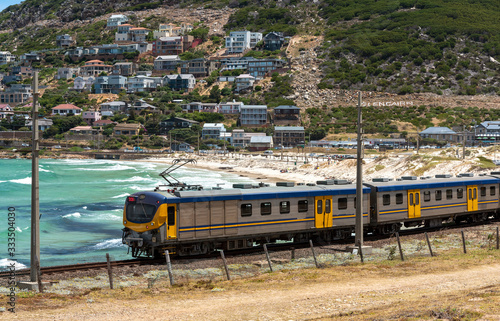 Glencairn, Cape Town, South Africa. December 2019. Coastal passenger train passing the resort of Glencairn on the coast to Simons Town where it terminates.