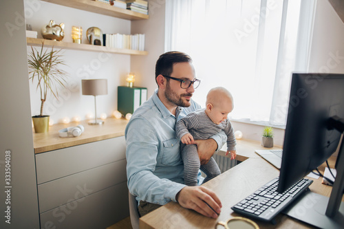 Canvas Print Young father working from home and babysitting his baby boy in the same time