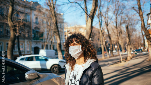 Portrait of young woman in face mask walking © progressman
