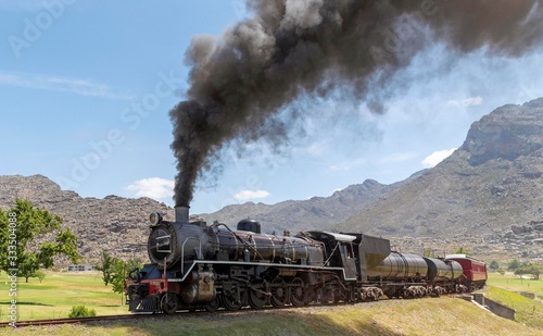Ceres, Western Cape, South Africa. December 2019.  Steam engine hauling passenger coaches to the annual excursion to the Cherry Festival on Ceres golf estate. Background of Michell's Pass.
