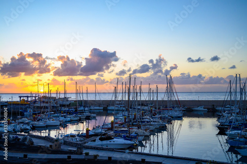 Lifestyle background, yachts and sail boats in ocean harbour on tropical island on sunrise