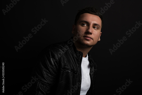 Studio shot of young man. Isolated on black background. he has a serious face, he is wearing a black T-shirt