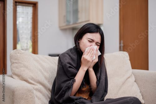 Portrait of a sneezing and sick flu young woman asian at home. Pandemic 2019 Coronavirus 2019-nCoV Concept.