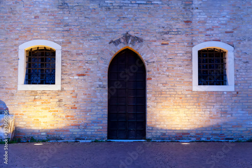 Porta e finestre del famoso trecentesco palazzo comunale, edificio gotico, della città di Portogruaro, Veneto, Italia. Fotografia notturna. © snake_xenzia