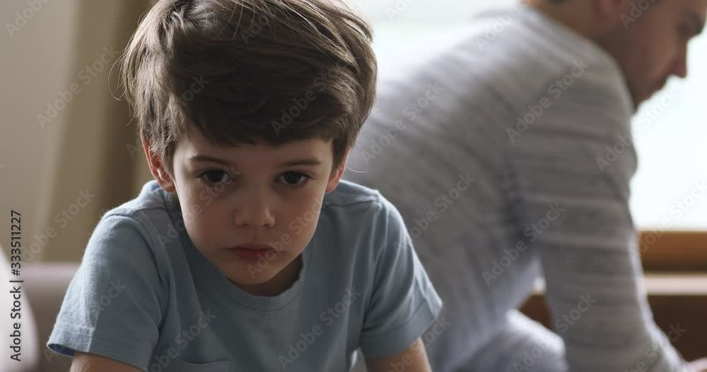 Head shot sad upset little preschool boy sitting on couch separately from angry dad, feeling stressed after quarrel. Abused two male generations family ignoring each other after misunderstanding. Head shot sad upset little preschool boy sitting on couch separately from angry dad, feeling stressed after quarrel. Abused two male generations family ignoring each other after misunderstanding.