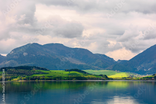 Fototapeta Naklejka Na Ścianę i Meble -  lake in mountains. cloudy day in springtime. beautiful scenery of high fatra mountains in dappled light. wonderful scenery of liptovska mara, slovakia