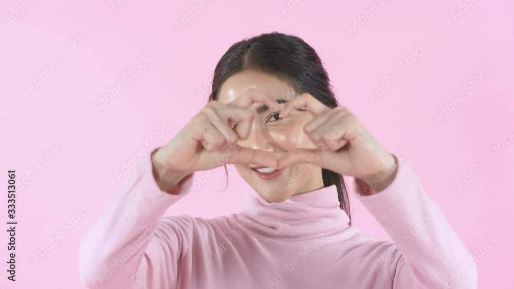 Beauty concept. A beautiful woman staring at the camera on a pink background. 4k Resolution. Beauty concept. A beautiful woman staring at the camera on a pink background. 4k Resolution.