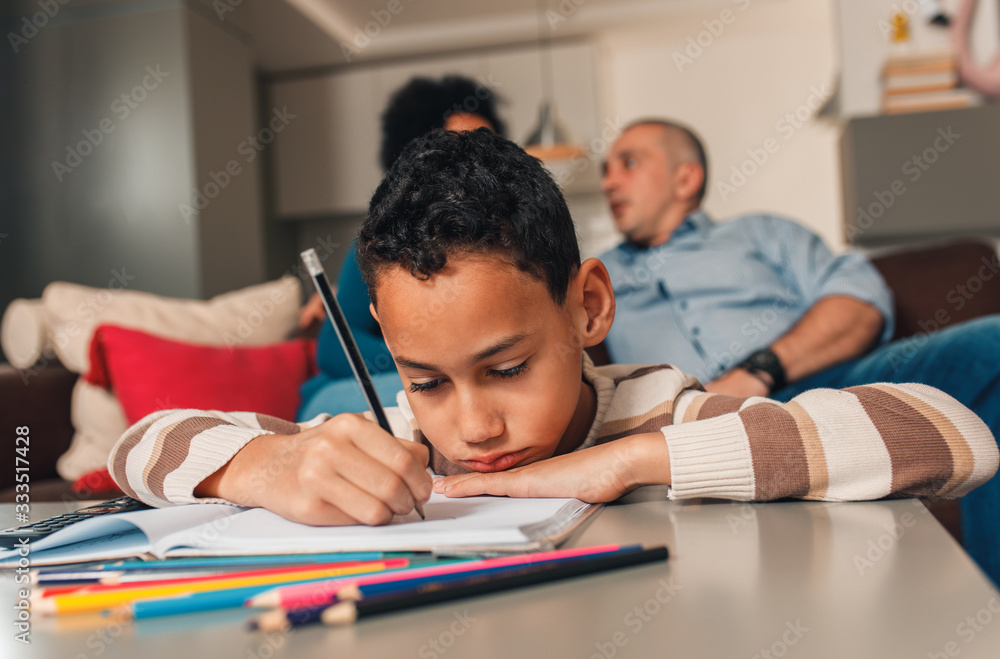 Parents helping their son with his homework at home in living room. Parents helping their son with his homework at home in living room.