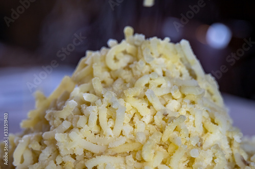 Close up of smoking hot boiled potato worms, just passed in the potato masher. Swirls of steam rising from the heap of mashed potatoes. photo