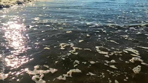 Water foam flowing with sunbeams, slow motion