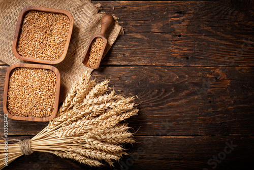 grains and wheat ears on a wooden table,