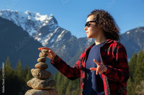 Girl with Balancing Rocks on the beach by the Alouette Lake during a sunny winter day. Taken in Golden Ears Provincial Park, near Vancouver, British Columbia, Canada. photo