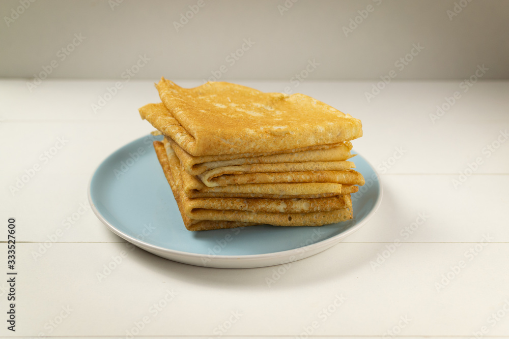 Pancakes (Russian Blini) with strawberry jam and tea on a white background. Breakfast. Сlose up. Pancakes (Russian Blini) with strawberry jam and tea on a white background. Breakfast. Сlose up.