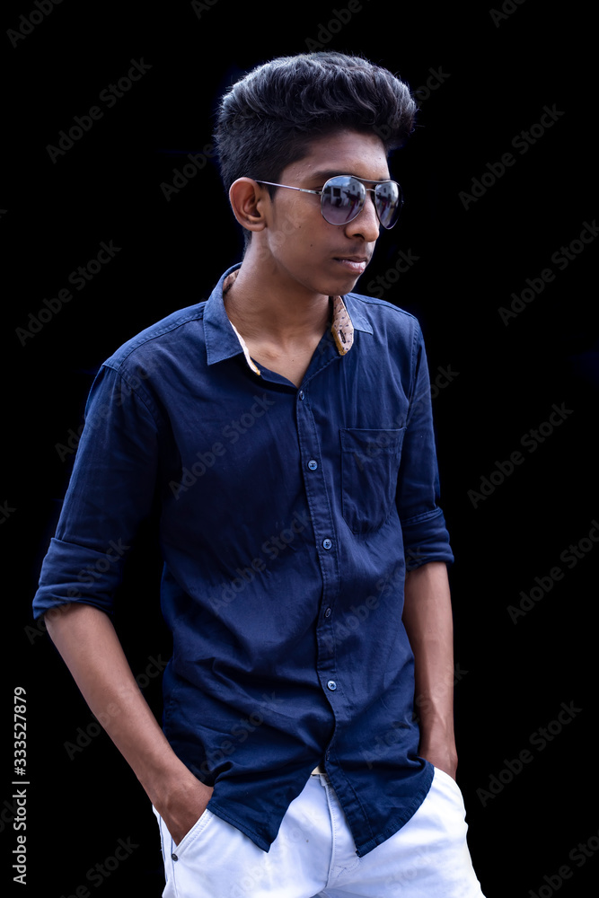 Stylish handsome young man and looking at down while standing against black background Stylish handsome young man and looking at down while standing against black background