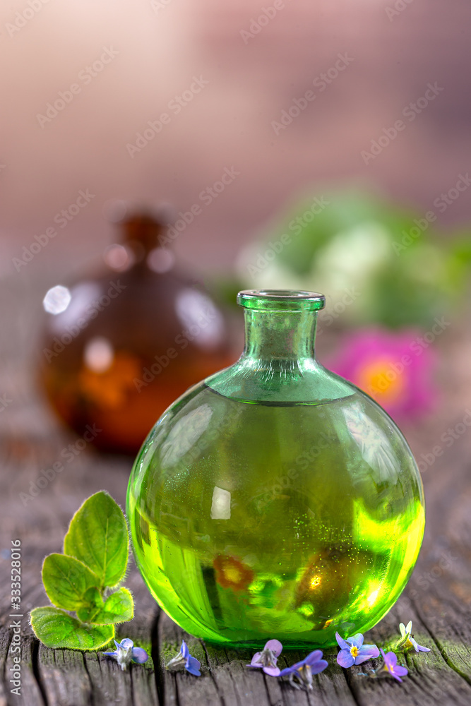 Alternative Medicine: Essential oil, on glass flask with fresh herbs and flowers on wooden background Alternative Medicine: Essential oil, on glass flask with fresh herbs and flowers on wooden background
