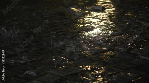 4K video of a torrential downpour onto cobblestone at night in the tropics. Raindrops highlighted against a dark background. Night time, low light video. Bad weather video.