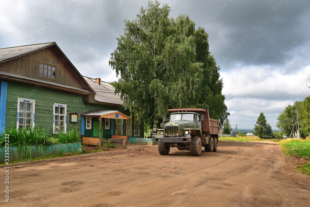 Russian village in the rays of the warm summer sun. Old wooden houses, fields and copses.