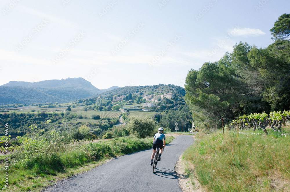 Female cyclist riding through mountain road forest