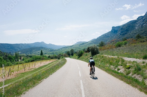 Female cyclist riding through mountain road forest