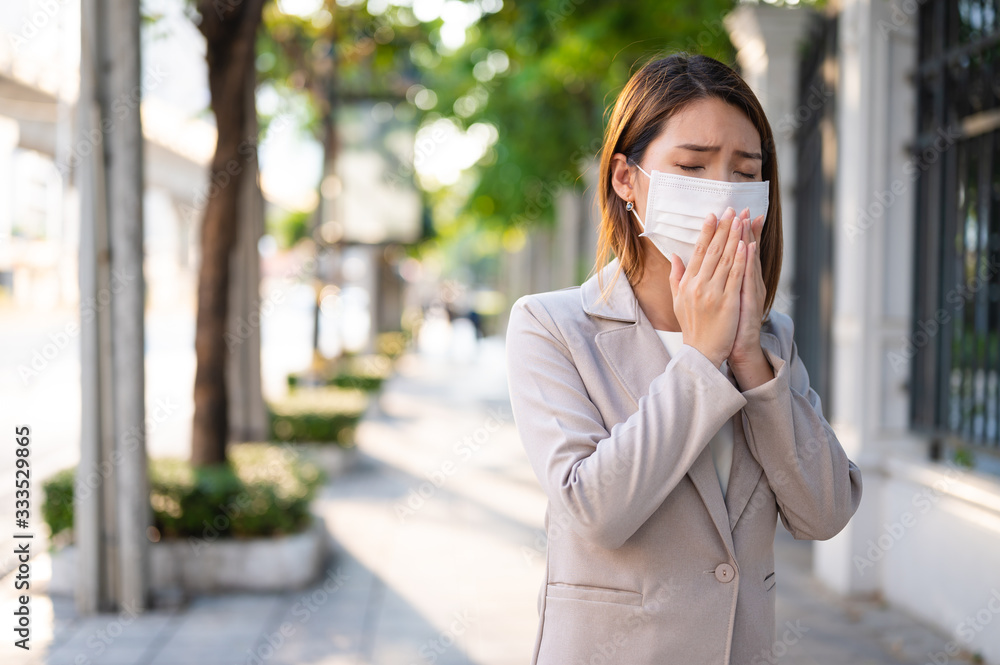 Young business woman wearing surgical mask and coughing while walking in public in Coronavirus or COVID-19 spreading situation Young business woman wearing surgical mask and coughing while walking in public in Coronavirus or COVID-19 spreading situation