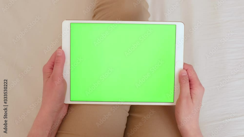 Woman with a tablet computer in hands with a green screen, chroma key.