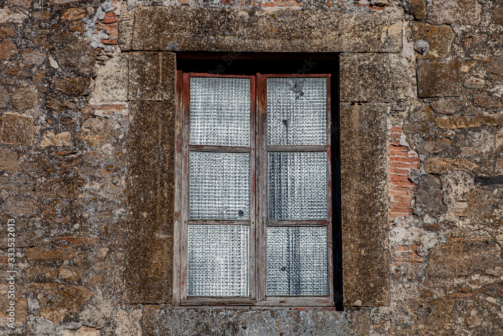 Antigua ventana de de madera vieja con cristales traslúcidos y pared de piedra