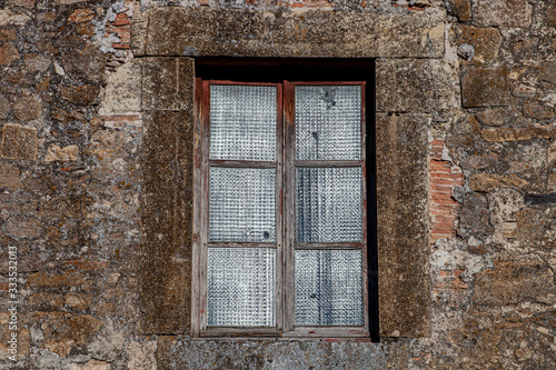 Antigua ventana de de madera vieja con cristales trasl  cidos y pared de piedra