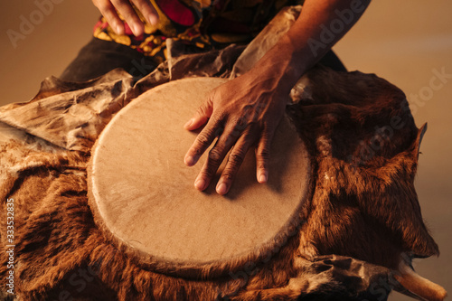 Fotografia Detail of african american man musician playing traditional drums at brown background