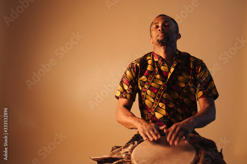 Φωτογραφία African american man musician playing traditional drums at brown background copy space