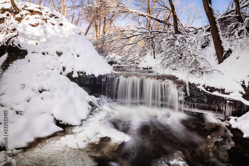 Tiny waterfall fed by the melting snow. Shot was taken at sunset. Warm light falls onto the cold snow and freezing water.