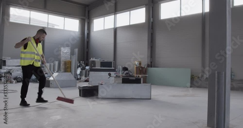 A cheerful and well-disposed worker dances with the sweeper while cleaning the deposit.