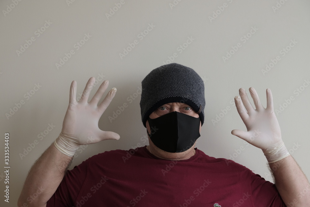 Portrait of a man protected from coronavirus. White, latex gloves. Hand protection against infections, viruses, germs. Isolation of the skin. On the face is a fabric mask. Glasses on the eyes. Symboli Portrait of a man protected from coronavirus. White, latex gloves. Hand protection against infections, viruses, germs. Isolation of the skin. On the face is a fabric mask. Glasses on the eyes. Symboli